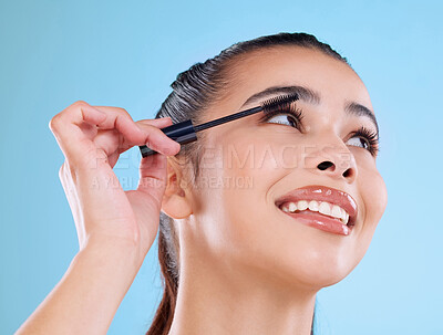Buy stock photo Studio shot of an attractive young woman applying mascara against a blue background