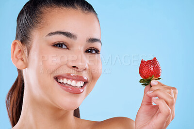 Buy stock photo Studio portrait of an attractive young woman posing with a strawberry against a blue background