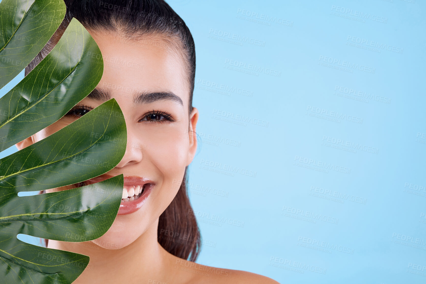 Buy stock photo Skincare, leaf and half portrait of woman with smile, mockup or natural benefits of organic cosmetics in studio. Beauty, dermatology and happy girl with green plants, healthy skin and blue background