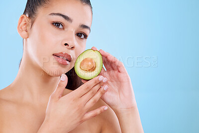 Buy stock photo Studio portrait of an attractive young woman posing with half an avo against a blue background