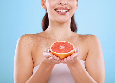 Buy stock photo Happy woman, hands and vitamin C with grapefruit for diet, nutrition or health on a blue studio background. Closeup of young female person with natural organic fruit for detox, collagen or skincare