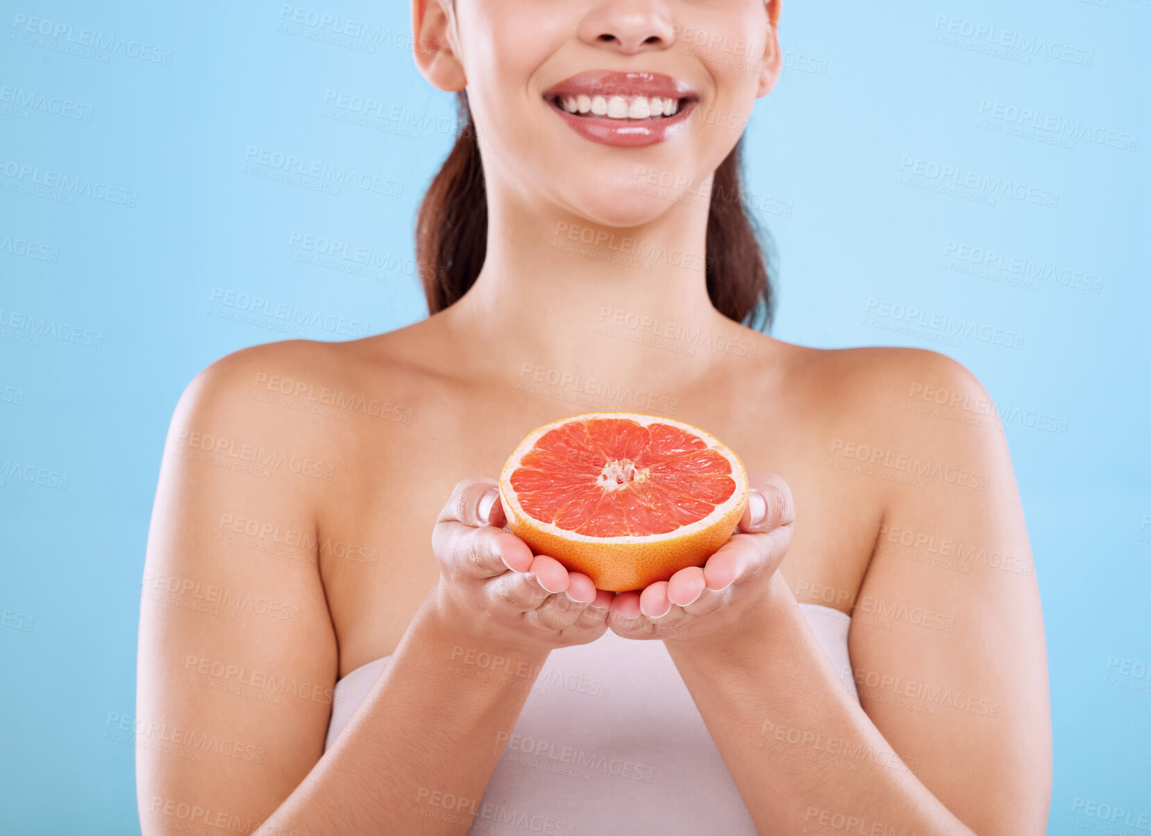 Buy stock photo Happy woman, hands and vitamin C with grapefruit for diet, nutrition or health on a blue studio background. Closeup of young female person with natural organic fruit for detox, collagen or skincare