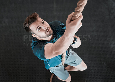 Buy stock photo Shot of a young man climbing a rope in the gym