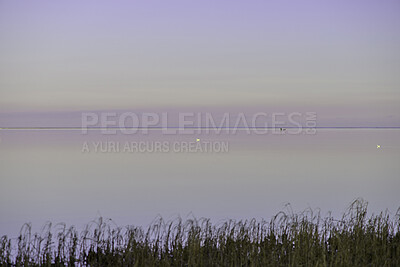 Buy stock photo Beautiful, isolated seascape of the calm beach and ocean or lake after sunset on a summer or spring day. Scenic view of nature and clear sky on the horizon of purple reflection over relaxing water.