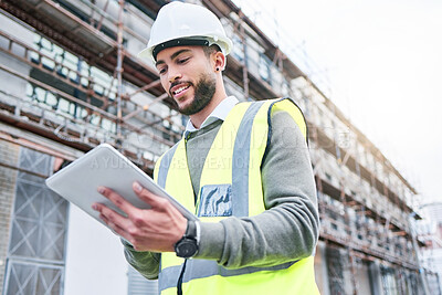 Buy stock photo Shot of a handsome male construction worker using a tablet while standing outside