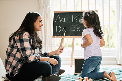 Buy stock photo Shot of a young mother helping her daughter with homework at home