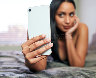 Buy stock photo Shot of an unrecognisable woman lying on the bed and using her cellphone to take sexy selfies