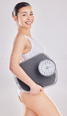Buy stock photo Shot of a woman holding a weight scale while posing against a studio background