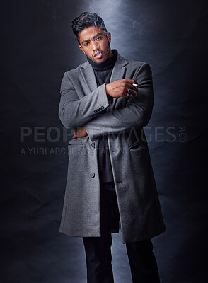 Buy stock photo Fashion, man smoking and dark studio with serious mafia leader, holding cigarette and cool stylish winter coat. Mysterious, trendy and edgy smoke for Indian mob, black background and confident model