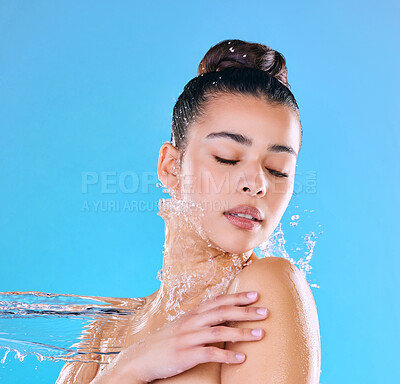 Buy stock photo Shot of a beautiful young woman being splashed with water against a blue background