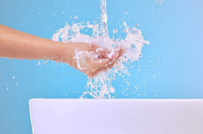 Buy stock photo Water splash, model and washing hands in studio for health, hygiene or wellness isolated on blue background. Sink, liquid and person cleaning for skincare, beauty and bath in bathroom for dermatology