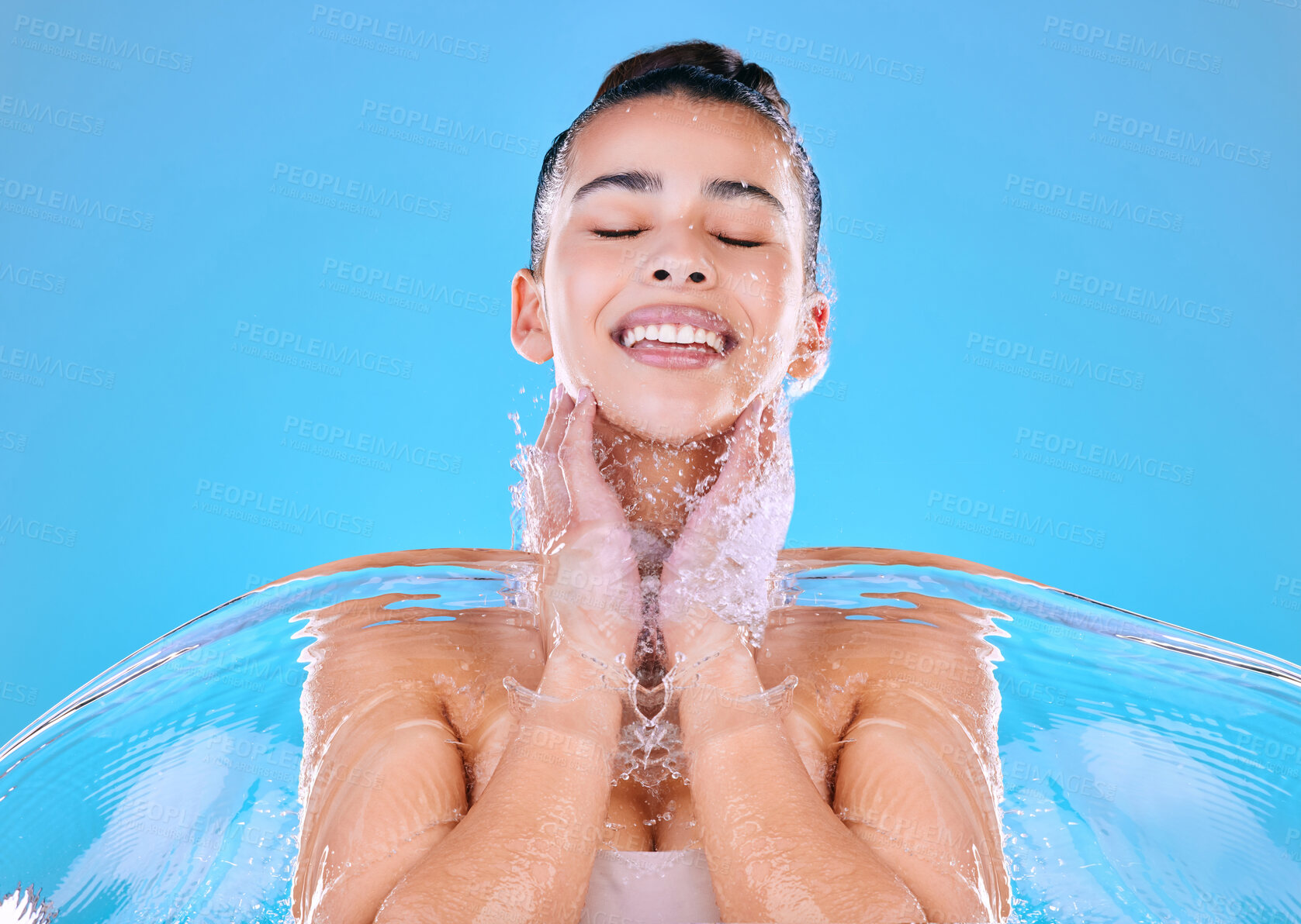 Buy stock photo Water, splash and woman with smile in studio for natural hydration, dermatology and skincare. Happy, shower and female person with liquid for hygiene, clean body and sustainability on blue background