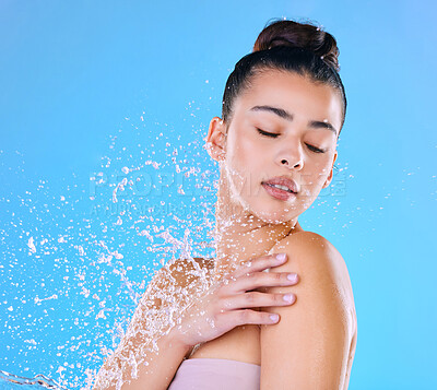 Buy stock photo Shot of a beautiful young woman being splashed with water against a blue background