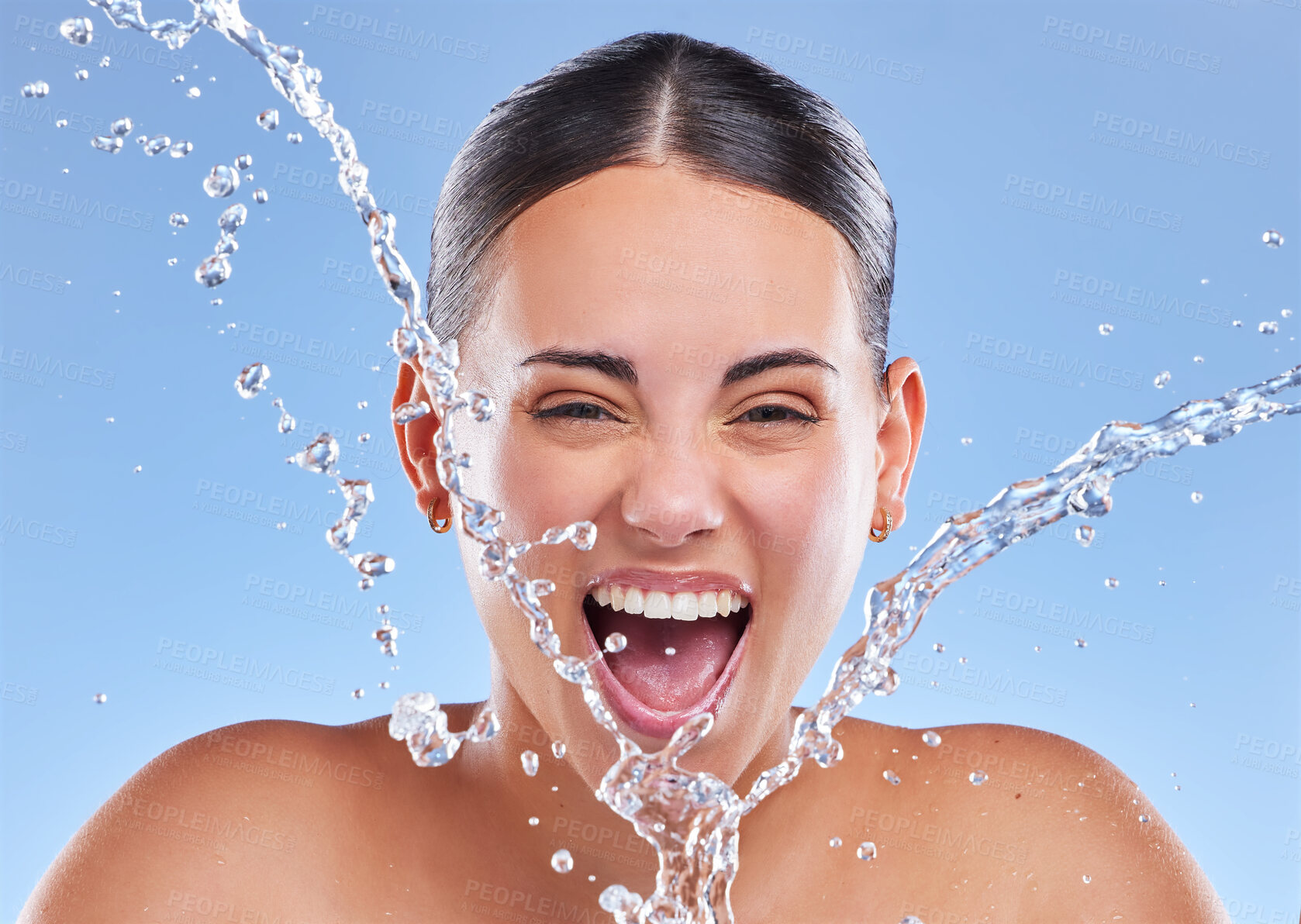 Buy stock photo Hydration, water splash and excited woman in studio for portrait, clear skin and rejuvenate on blue background. Skincare, facial and happy girl for cleaning with refresh, wellness and freshness