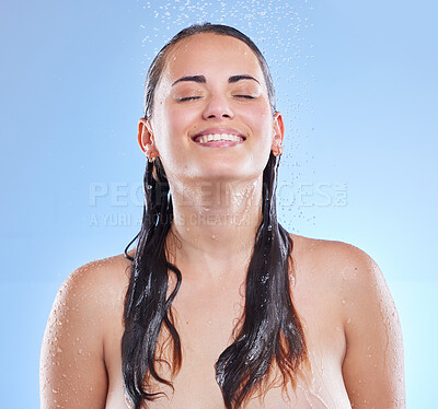 Buy stock photo Shot of a beautiful young woman enjoying a refreshing shower against a blue background