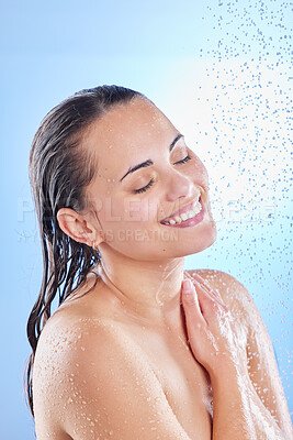 Buy stock photo Shot of a beautiful young woman enjoying a refreshing shower against a blue background