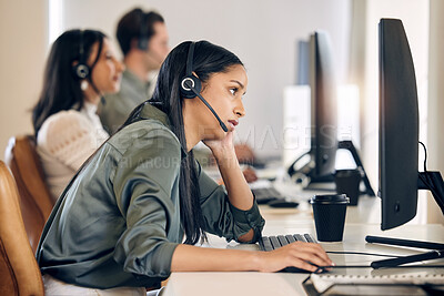 Buy stock photo Shot of a young call centre agent looking bored while working on a computer in an office