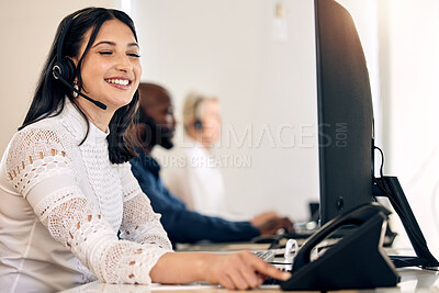 Buy stock photo Shot of a young call centre agent using a telephone while working on a computer in an office
