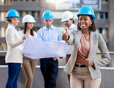 Buy stock photo Shot of a young female architect showing a thumbs up while working with coworkers against a city background