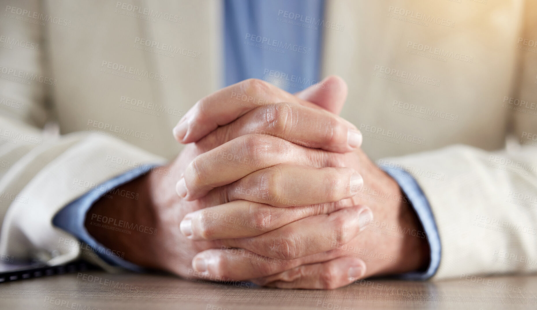 Buy stock photo Cropped shot of an unrecognisable businessman sitting alone in his office with his hands clasped