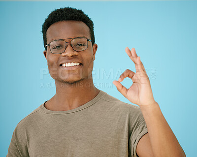 Buy stock photo Portrait, smile and black man with ok sign in studio for thank you, winner support or agreement of announcement. Happy, African person and glasses with yes hand gesture, like icon and blue background