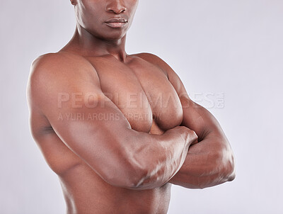 Buy stock photo Studio shot of a muscular young man posing with his arms crossed against a grey background