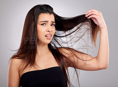 Buy stock photo Studio portrait of an attractive young woman having a bad hair day against a grey background
