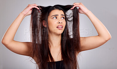 Buy stock photo Studio shot of an attractive young woman having a bad hair day against a grey background
