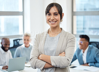 Buy stock photo Portrait of a young businesswoman standing with her arms crossed in an office with her colleagues in the background