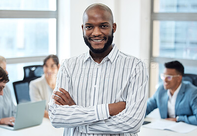Buy stock photo Portrait of a young businessman standing with his arms crossed in an office with his colleagues in the background