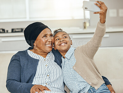 Buy stock photo Shot of a grandmother taking a selfie with her granddaughter on a sofa at home