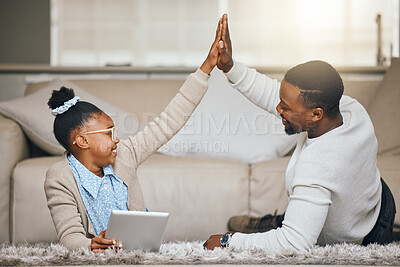 Buy stock photo Shot of a young father and daughter giving each other a high five while using a digital tablet at home