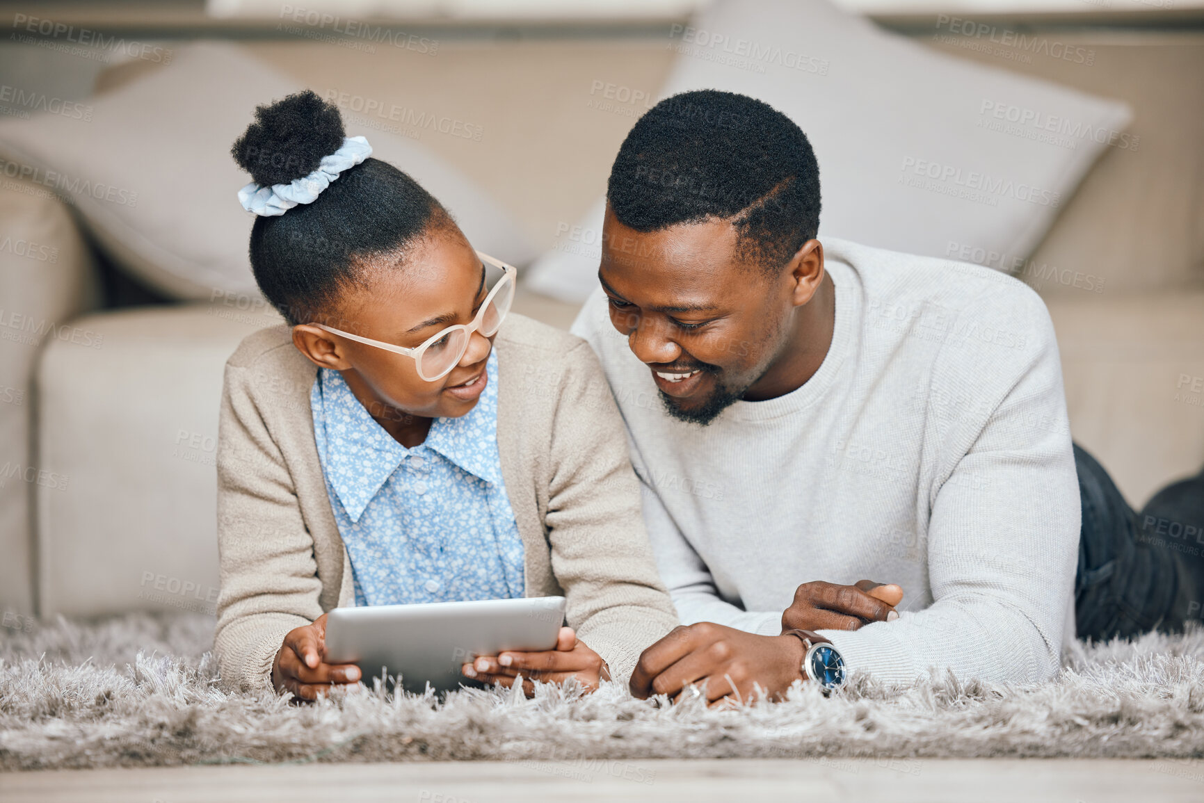 Buy stock photo Shot of a young father and daughter using a digital tablet together at home