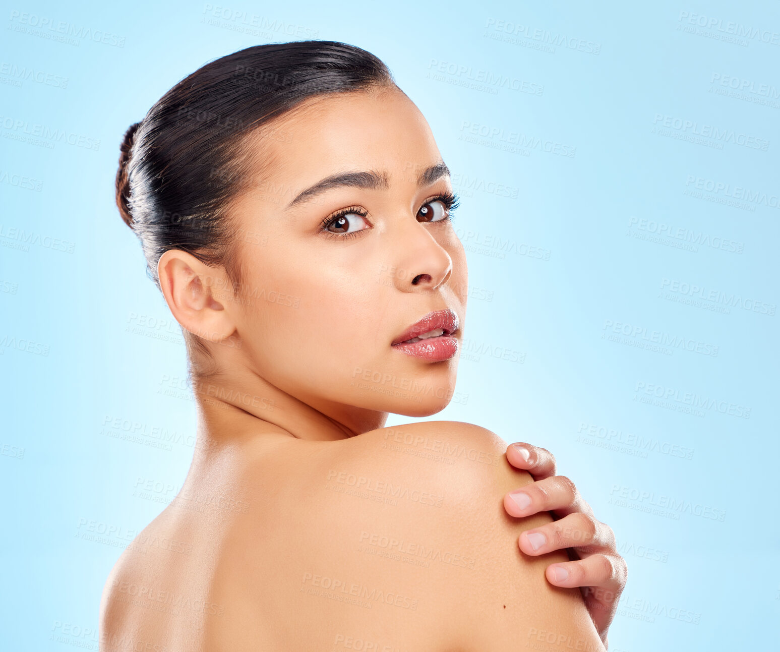 Buy stock photo Studio portrait of an attractive young woman posing against a blue background