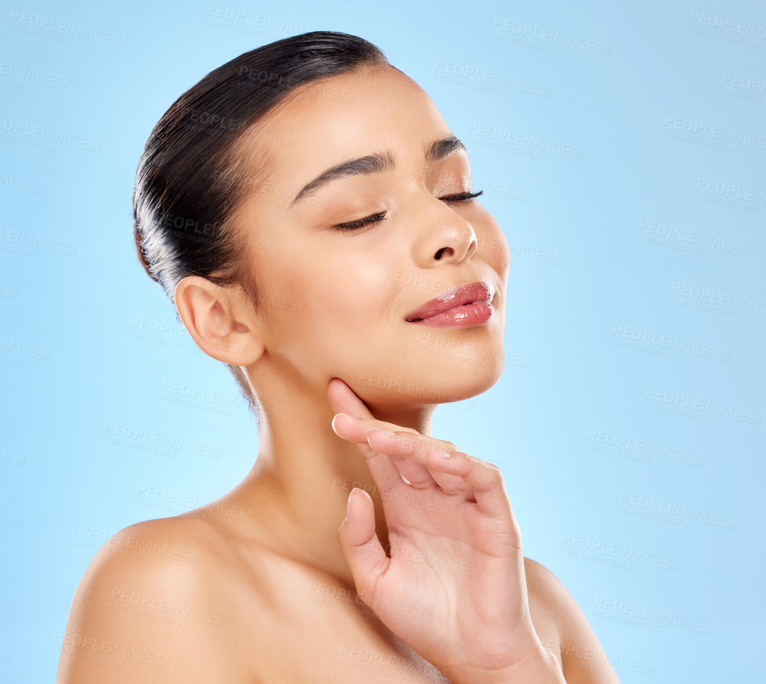 Buy stock photo Studio shot of an attractive young woman posing against a blue background