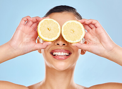 Buy stock photo Studio shot of an attractive young woman posing with lemon against a blue background