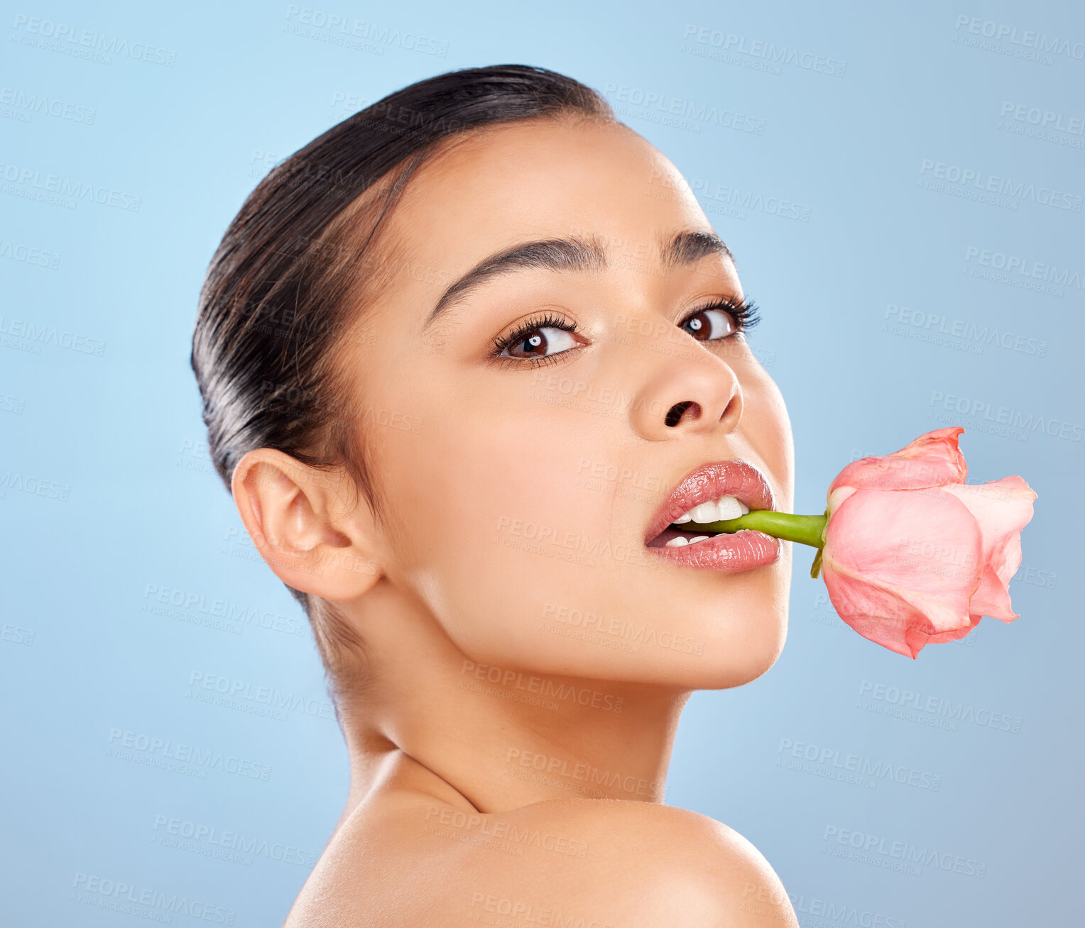 Buy stock photo Woman, portrait and rose skincare in studio, mouth and sustainable cosmetics on blue background. Female person, plant and organic facial treatment, pink dermatology and flower for eco friendly makeup