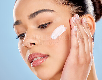 Buy stock photo Thinking, woman and face cream in studio for skincare, product or cosmetics and dermatology. Model girl, moisturiser or lotion and idea for facial with luxury, glow and benefits by blue background