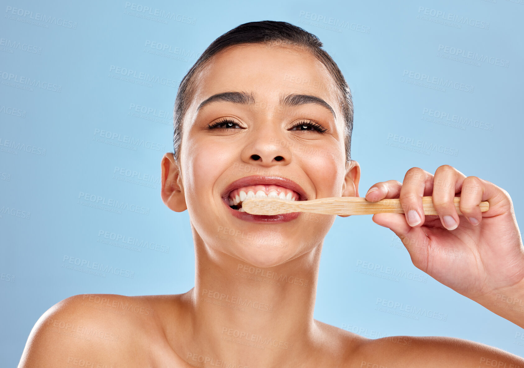 Buy stock photo Woman, portrait and brushing teeth in studio with hand, dental care and mouth wellness for hygiene. Bamboo, toothbrush and eco friendly product on blue background, cleaning and happy for oral health