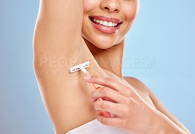 Buy stock photo Studio shot of an unrecognisable woman shaving her underarm against a blue background