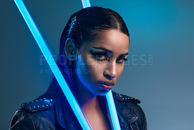 Buy stock photo Conceptual portrait of a stylish young woman posing in studio against a blue background