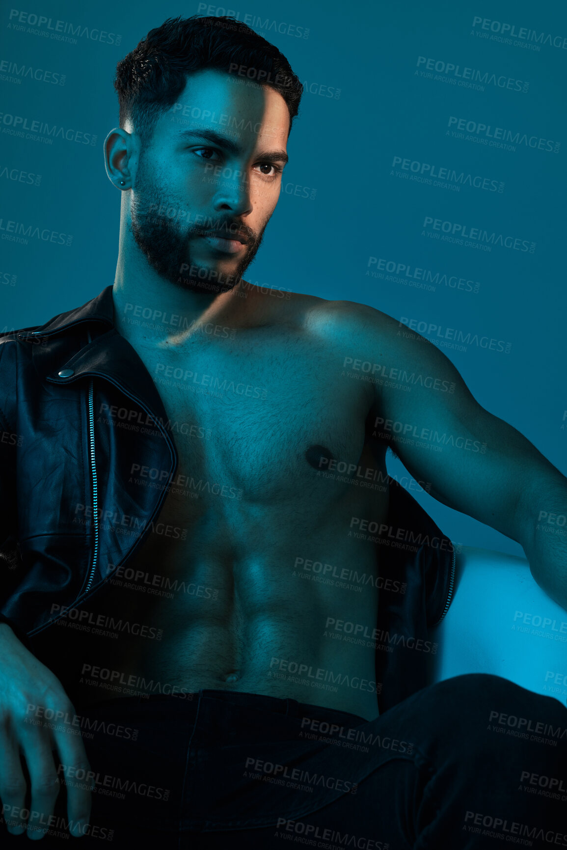 Buy stock photo Conceptual shot of a stylish young man posing in studio against a blue background