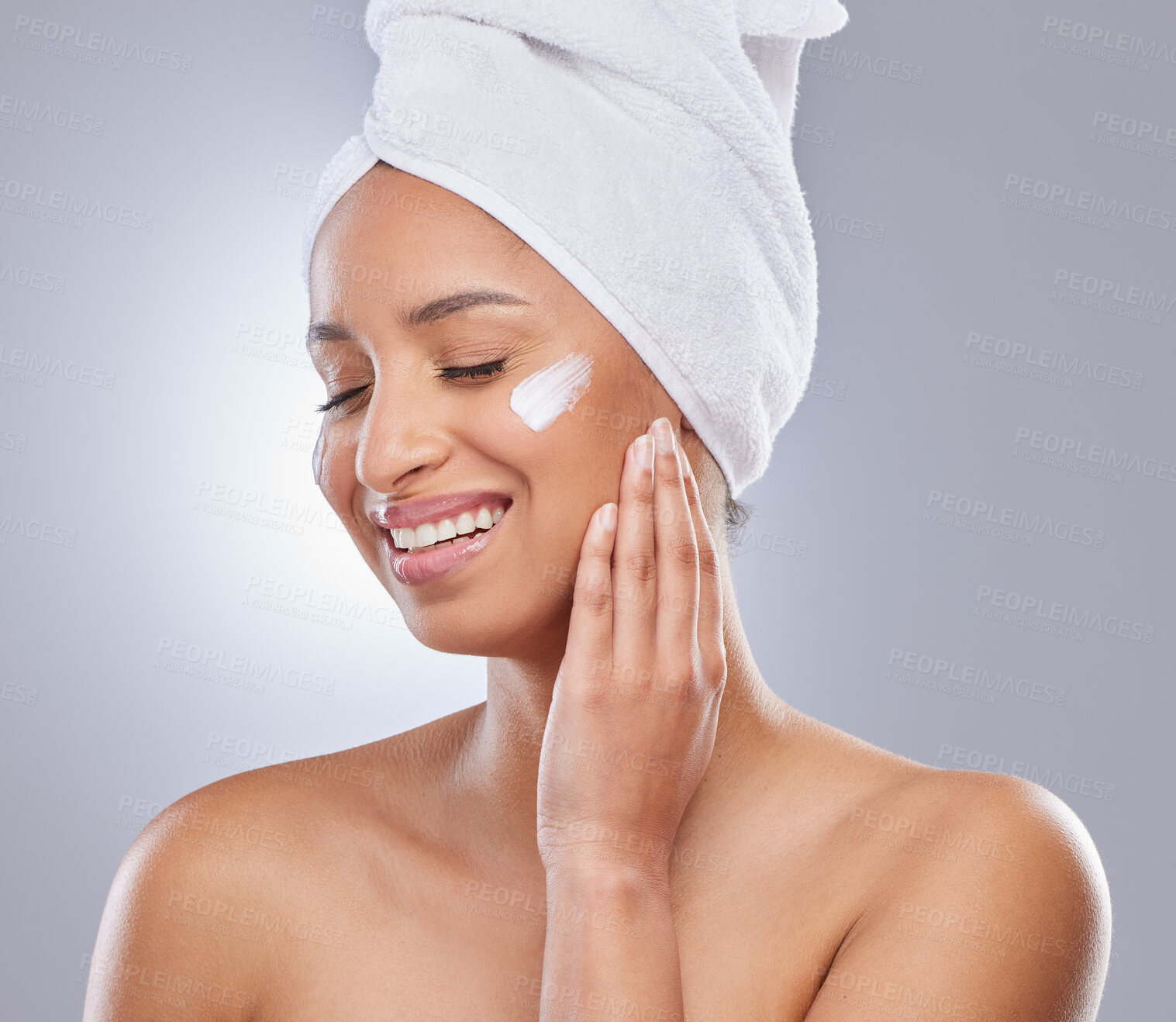 Buy stock photo Studio, woman and towel for cream or cosmetics, moisturizer and hand on white background. Skincare, dermatology and beauty for female person, smile or relax for lotion with glow and product on face