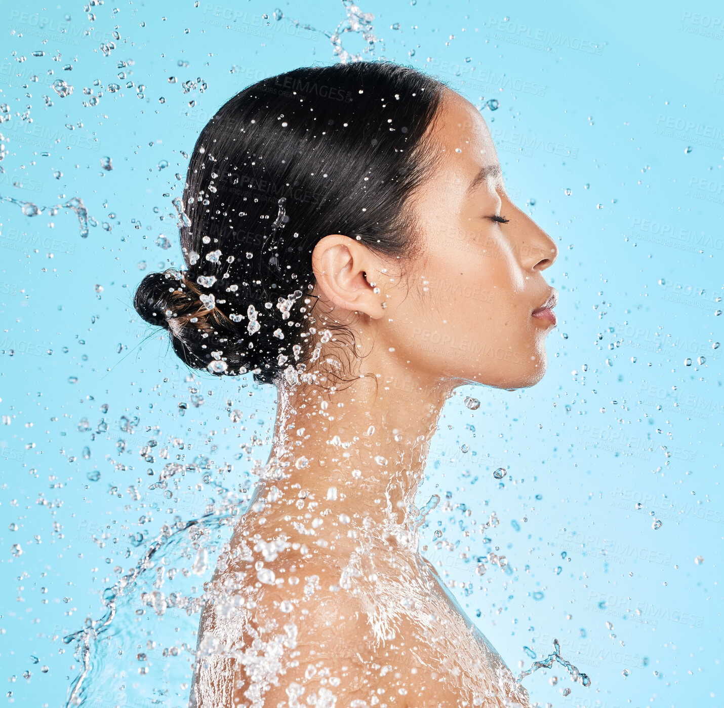 Buy stock photo Beauty, water and face profile of woman on blue background for wellness, healthy skin and cleaning. Bathroom, shower and female person with splash for facial grooming, washing and skincare in studio