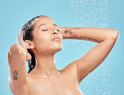 Buy stock photo Shot of a beautiful young woman enjoying a shower against a blue background