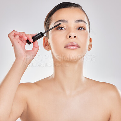 Buy stock photo Shot of a young woman applying makeup to her face against a grey background