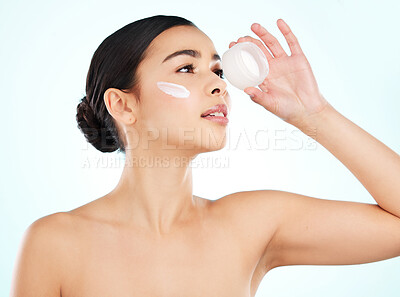 Buy stock photo Studio shot of an attractive young woman posing with a contrainer of face moisturizer against a light background