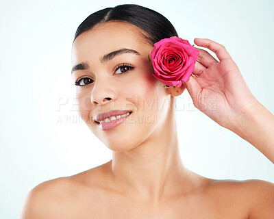 Buy stock photo Studio portrait of an attractive young woman posing with a pink rose against a light background