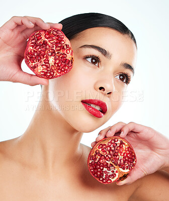 Buy stock photo Studio shot of an attractive young woman posing with a pomegranate against a light background