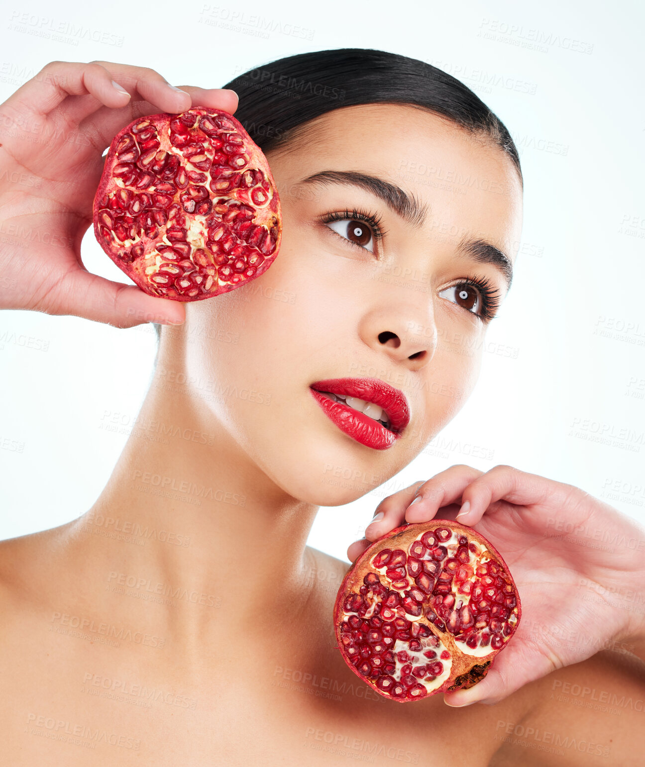 Buy stock photo Studio shot of an attractive young woman posing with a pomegranate against a light background